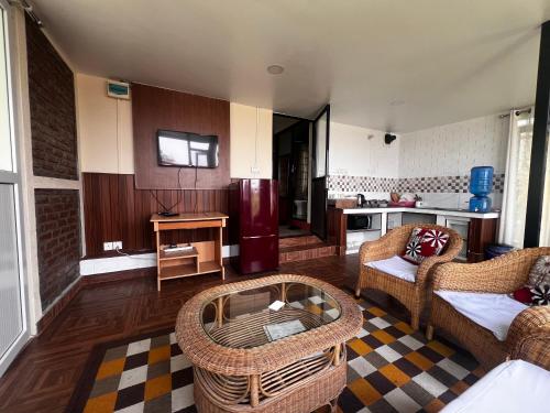 a living room with rattan furniture and a kitchen at Avocado Accommodations - Tiny Cottages in Khadkagaon