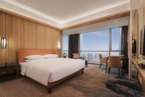 a bedroom with a large white bed and a dining room at Hyatt Regency Shanghai Wujiaochang in Shanghai
