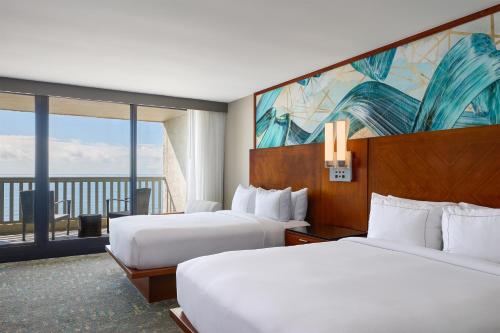 a hotel room with two beds and a large window at Hilton Beachfront Resort & Spa Hilton Head Island in Hilton Head Island