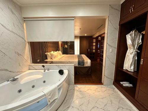 ein Badezimmer mit Badewanne und ein Bett in einem Zimmer in der Unterkunft Madison Crown Hotel in Angeles