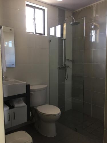 a bathroom with a toilet and a glass shower at Hotel Las Caobas in San Francisco de Macorís