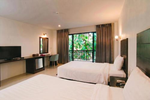 a hotel room with two beds and a television at Wilacha Chiang Rai in Chiang Rai