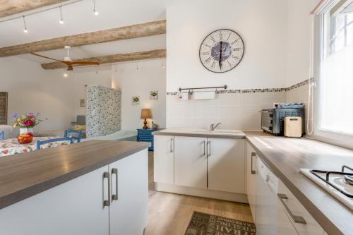 a kitchen with white cabinets and a clock on the wall at Gîte le Petit Luberon - Lisianthus in Cabrières-dʼAvignon
