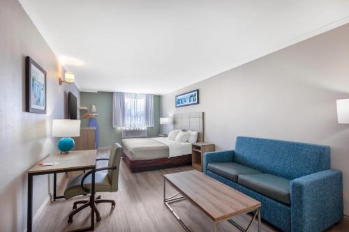 a living room with a blue couch and a bed at Quality Inn & Suites in Niagara Falls