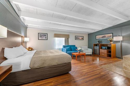a hotel room with a bed and a blue chair at Quality Inn & Suites Kansas City - Independence I-70 East in Independence