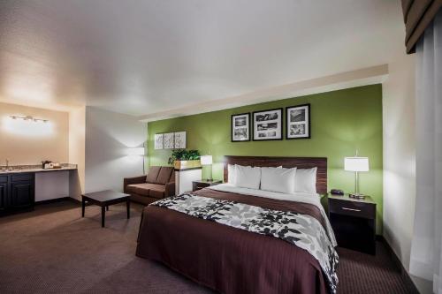 a hotel room with a bed and a green wall at Sleep Inn & Suites Tulsa Central I-44 in Tulsa