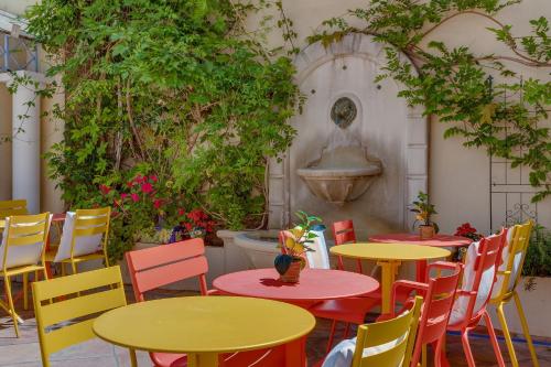 a patio with tables and chairs and a fountain at Hôtel de la Fontaine in Nice