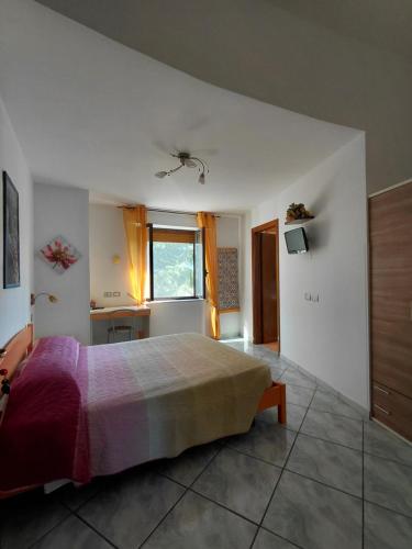 a bedroom with a bed and a desk and a window at La Cascina Camere in Agerola