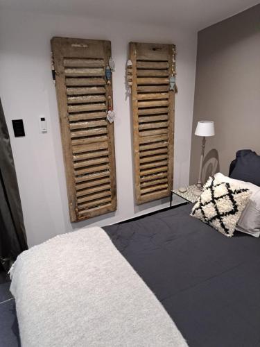 a bedroom with two wooden shuttered windows and a bed at Le clos d'oli in Wamin
