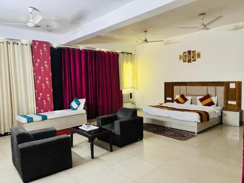 a bedroom with a bed and a couch and a chair at ADA Residency in Noida