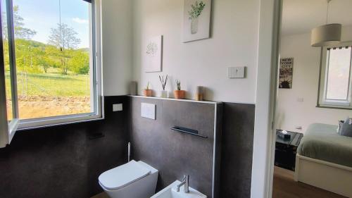 a bathroom with a toilet and a window and a bed at Bobbio Relax in Bobbio