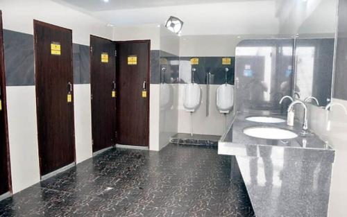 a bathroom with three sinks and urinals and toilets at Hotel Aam Bagh & Jain Shikanji in Kot Pūtli