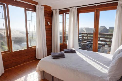 a bedroom with a bed in a room with windows at Beach Cabin with a pool in Port Alfred