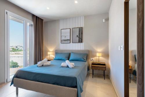 a bedroom with a blue bed and a large window at Brezza Apartments in Santa Flavia