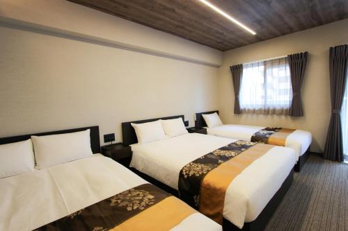 a hotel room with two beds and a window at INNEST Hakata in Fukuoka