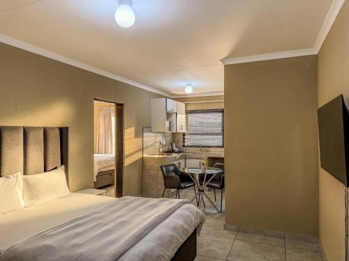 a bedroom with a bed and a kitchen with a table at Cosmo Sleepover in Roodepoort