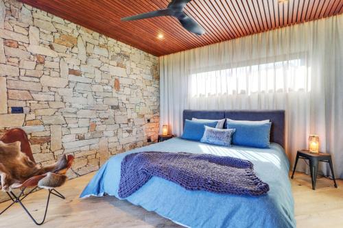 a bedroom with a bed and a stone wall at BullerRoo Luxury Chalet & Cottage Farmstay in Barwite