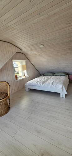 a bed in a room with a wooden ceiling at 3 ruoniai in Palanga