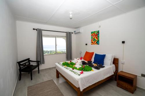 a bedroom with a bed and a chair and a window at Wild Vanilla Apartment in Beau Vallon
