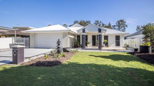 a white house with a lawn in front of it at Blissful Birdsong Escape in Banksia Beach