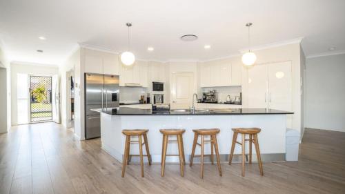 a kitchen with white cabinets and bar stools at Blissful Birdsong Escape in Banksia Beach