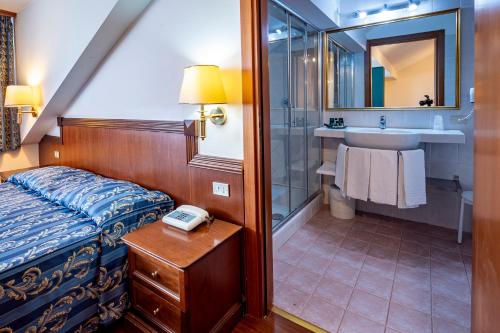a bedroom with a bed and a bathroom with a sink at Hotel Corona in Pescasseroli