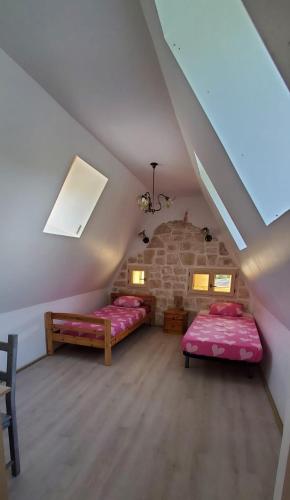a attic room with two beds and a stone wall at La maison de Coq-licot ! in Salignac Eyvigues