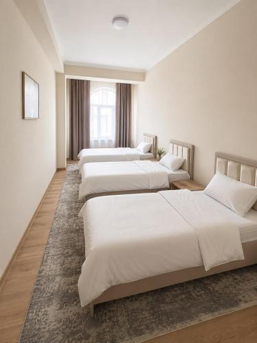 a row of four beds in a room at Datka Hotel in Bishkek