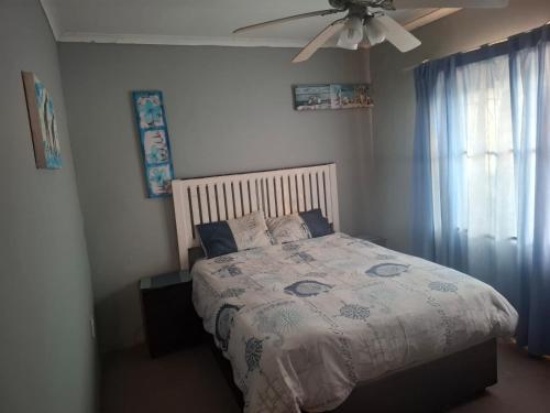 a bedroom with a bed and a ceiling fan at Over the Rainbow Guest House in Hibberdene
