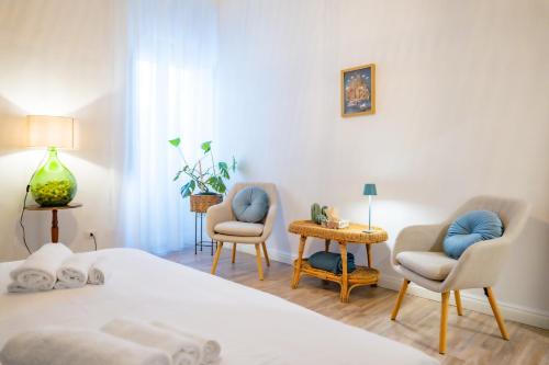 a bedroom with a bed and two chairs and a table at Inderooms Carloforte in Carloforte