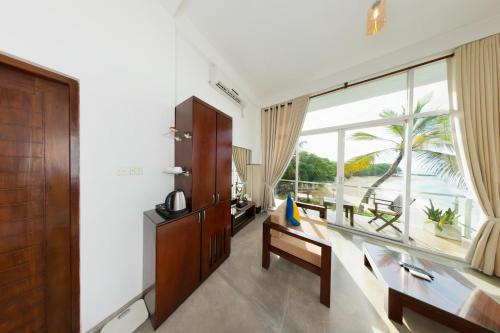 a living room with a large window and a table and bench at Garton's Cape in Ahangama