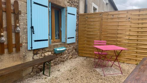 a pink table and chairs in front of a fence at La Petite Maison - 4 voyageurs in Voudenay-lʼEglise