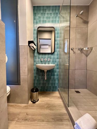 a bathroom with a sink and a glass shower at THE Pretoria Hotel in Pretoria