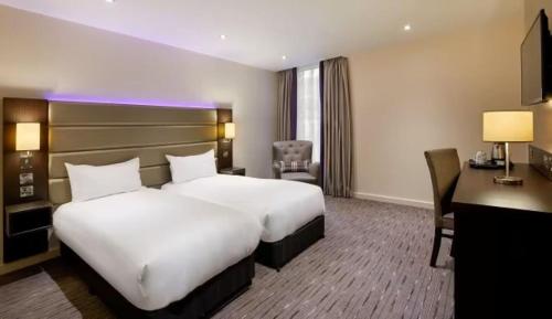 a hotel room with two beds and a desk at Wirral Park Hotel in Greasby