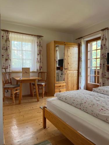 a bedroom with a bed and a table and a desk at Guggenbergerhof in Maria Luggau