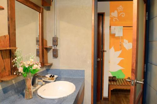 a bathroom with a sink and a vase of flowers at Khom Chiang Mai in Chiang Mai