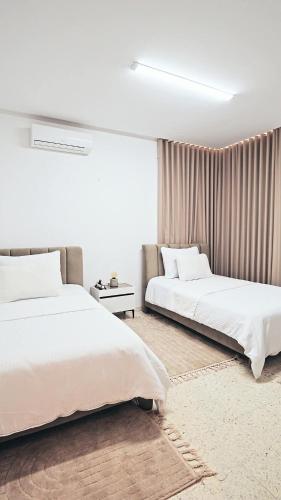 two beds in a room with white walls at chez moi sfax ville in Sfax