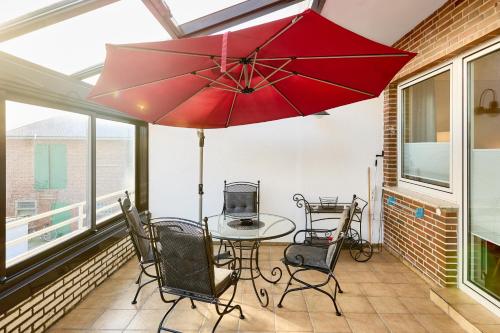 a patio with a table and chairs and a red umbrella at Haus Schildt, FeWo 8 in Duhnen