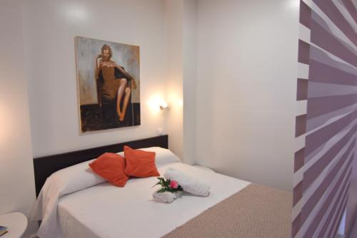 a bedroom with a bed with orange pillows and a painting at RNET - IR29218 Studios Roses Costa Brava in Roses