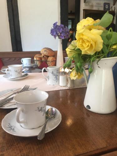 einen Tisch mit einer Tasse und eine Vase mit Blumen in der Unterkunft Historische Mühle Vogelsang in Brodenbach