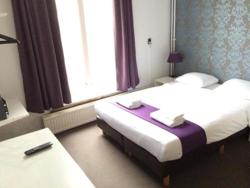 a hotel room with two beds and a table at Hotel Bellington in Amsterdam