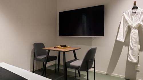 a table with chairs and a television and a coat on a wall at Anook Hotel Ulsan Mugeo in Ulsan