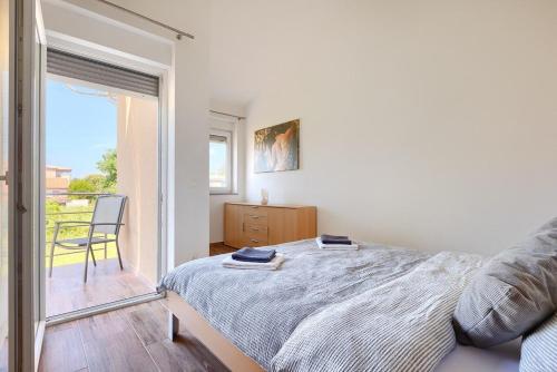 a white bedroom with a bed and a balcony at Villa Lara 1 in Ližnjan