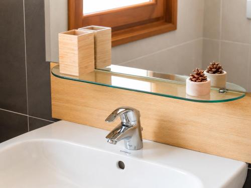 a sink in a bathroom with a mirror and a sink at Hotel Radis in Forni di Sotto