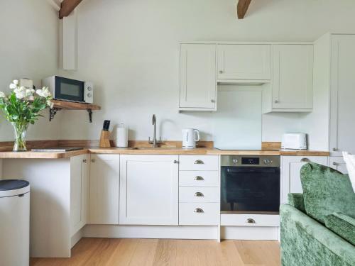 a kitchen with white cabinets and a green couch at Harvest - Ukc9523 in Barnstaple