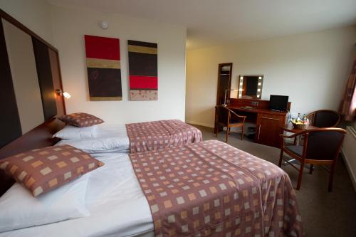 a hotel room with two beds and a desk at Normandy Hotel (Near Glasgow Airport) in Paisley