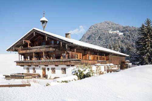 a log cabin in the snow with a mountain at Hochmuthhof in Reith im Alpbachtal