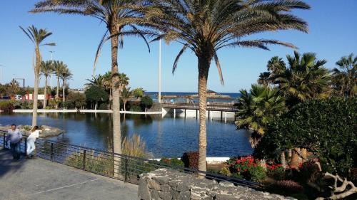 two people walking by a river with palm trees at Villa con Piscina ,Vista Mar y campo de golf in Caleta De Fuste