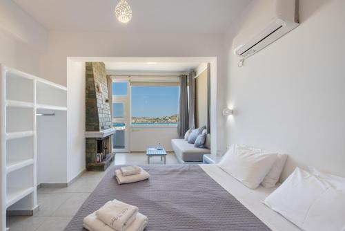 a white bedroom with a bed and a living room at Crystal Dream Paros in Kampos Paros