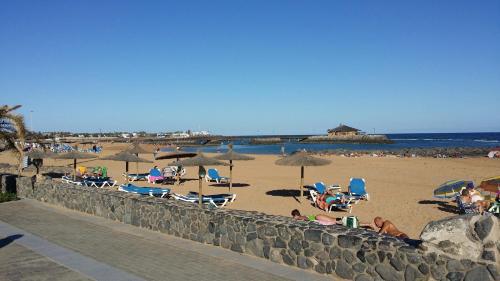 a beach with people sitting in chairs and umbrellas at Villa con Piscina ,Vista Mar y campo de golf in Caleta De Fuste